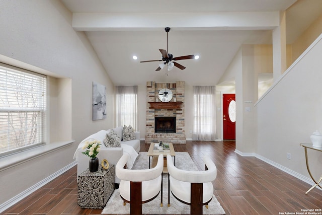 living room with lofted ceiling with beams, a stone fireplace, and ceiling fan