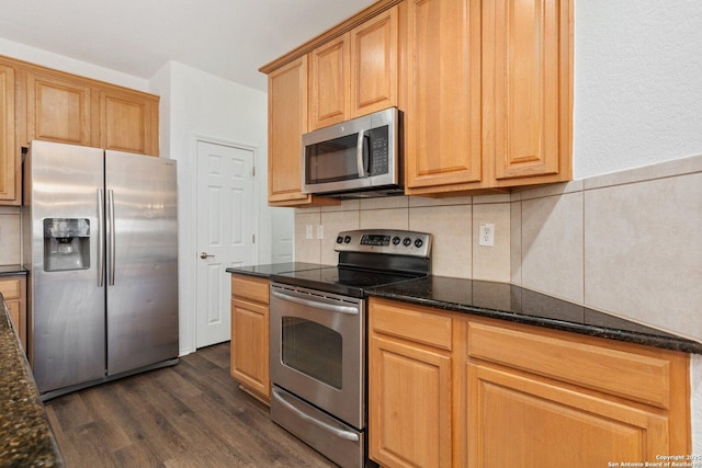 kitchen featuring dark wood-style floors, dark stone countertops, stainless steel appliances, and backsplash