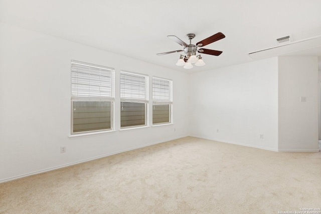 spare room with carpet floors, ceiling fan, visible vents, and baseboards