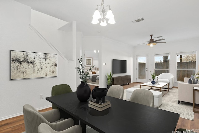 dining space featuring ceiling fan with notable chandelier, visible vents, baseboards, and wood finished floors