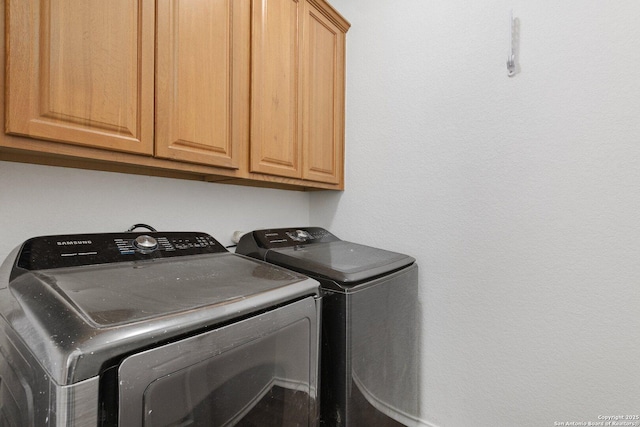 clothes washing area with independent washer and dryer and cabinet space