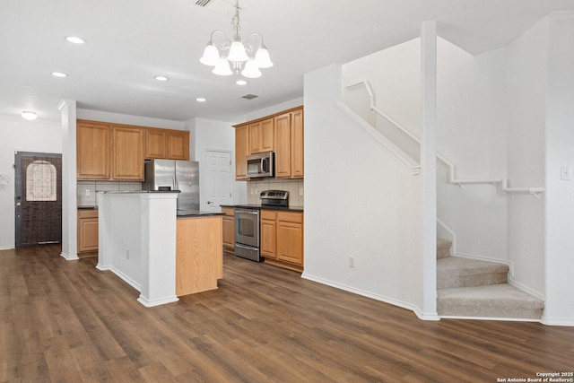 kitchen with dark wood-style flooring, tasteful backsplash, dark countertops, appliances with stainless steel finishes, and a chandelier