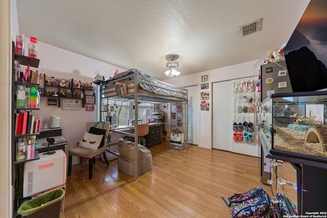 bedroom featuring hardwood / wood-style flooring, multiple closets, and a textured ceiling