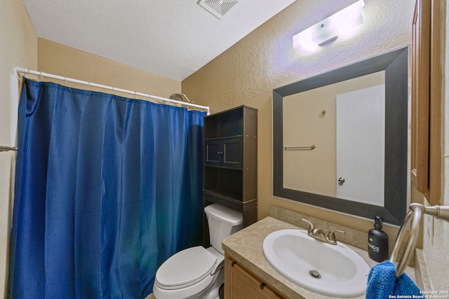 bathroom featuring vanity, walk in shower, a textured ceiling, and toilet