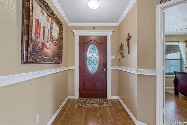 entryway featuring wood-type flooring, ornamental molding, and a textured ceiling