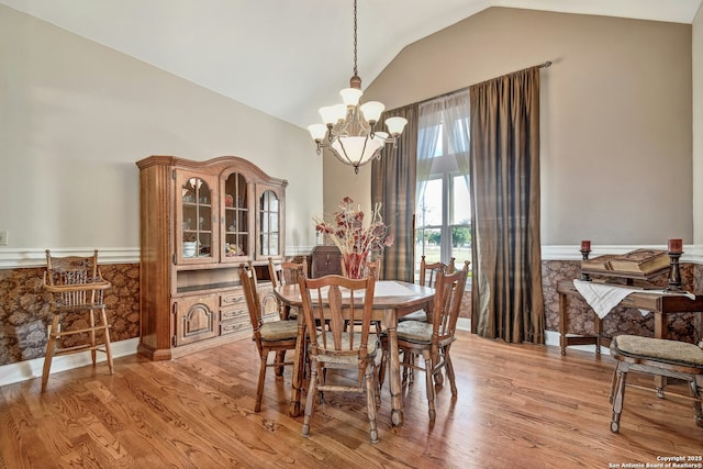 dining room featuring an inviting chandelier, light hardwood / wood-style floors, and vaulted ceiling