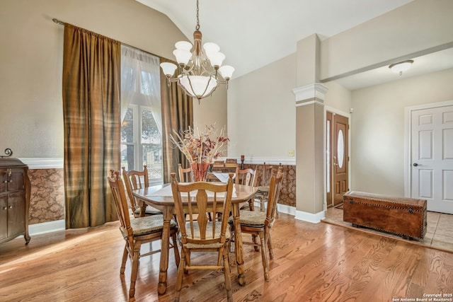 dining area with an inviting chandelier, vaulted ceiling, decorative columns, and light wood-type flooring