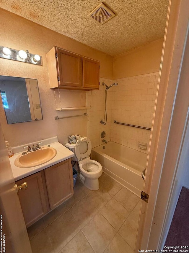 full bathroom featuring vanity, a textured ceiling, tiled shower / bath, tile patterned flooring, and toilet