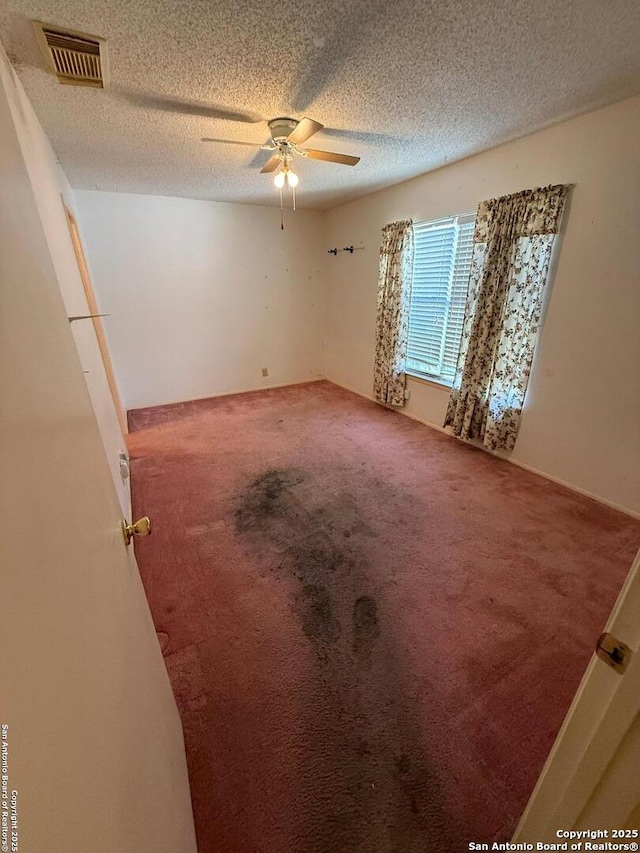 carpeted empty room with ceiling fan and a textured ceiling