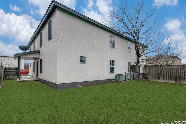 rear view of property with central AC, a patio, and a lawn