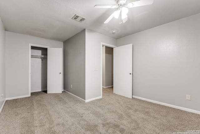 unfurnished bedroom featuring ceiling fan, a closet, and light carpet