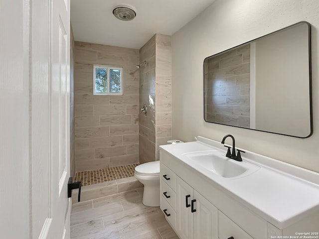 bathroom with vanity, tiled shower, and toilet