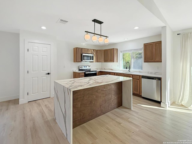 kitchen with pendant lighting, appliances with stainless steel finishes, light hardwood / wood-style floors, and a kitchen island