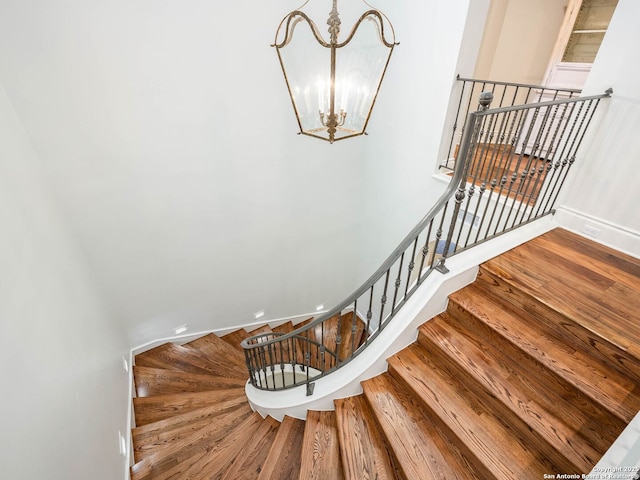 staircase with hardwood / wood-style flooring and an inviting chandelier