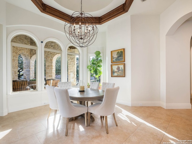tiled dining area featuring a tray ceiling, ornamental molding, and a chandelier