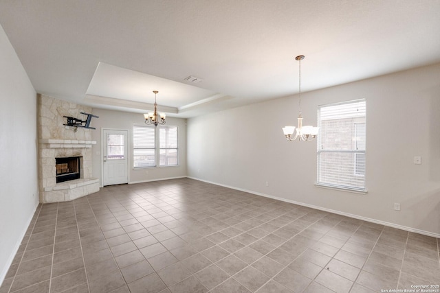 unfurnished living room featuring light tile patterned floors, a fireplace, a chandelier, and a tray ceiling