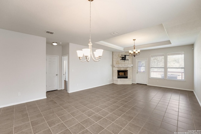 unfurnished living room with tile patterned flooring, a notable chandelier, a fireplace, and a tray ceiling