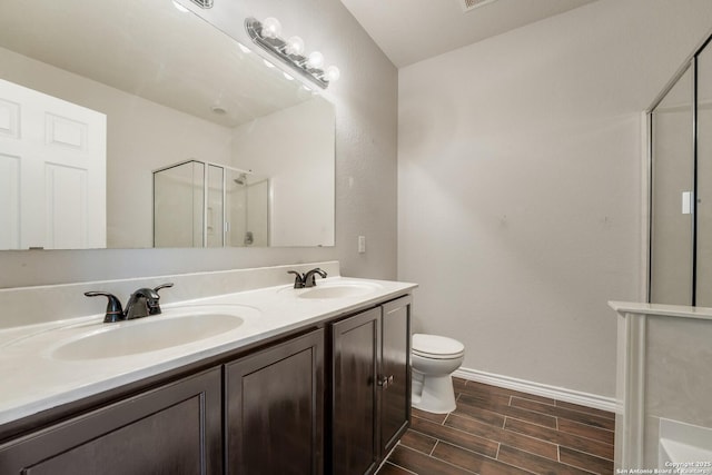 bathroom featuring vanity, a shower with door, and toilet