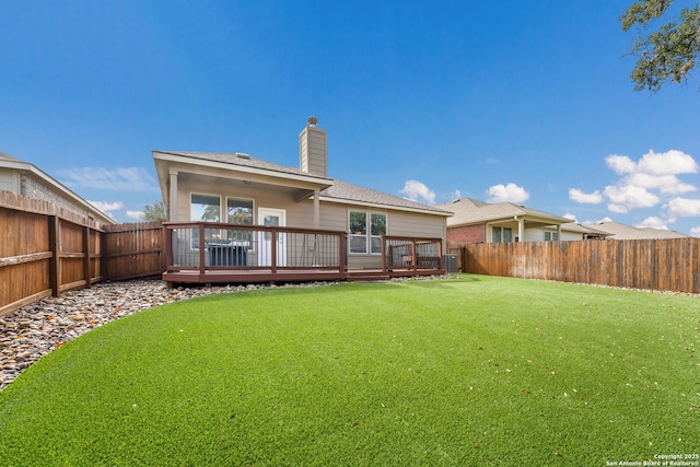 back of property with a wooden deck, a yard, and central AC