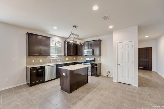 kitchen with appliances with stainless steel finishes, backsplash, hanging light fixtures, a center island, and dark brown cabinets