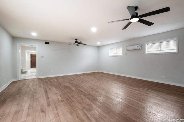 unfurnished room featuring ceiling fan, light hardwood / wood-style floors, and a wall mounted AC