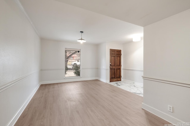 unfurnished room featuring ornamental molding and light wood-type flooring