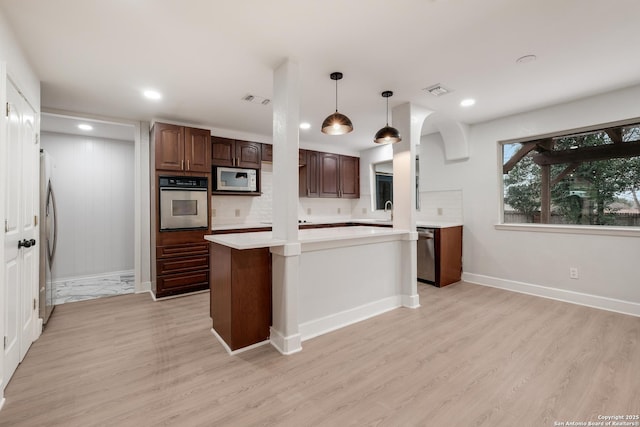 kitchen featuring dark brown cabinetry, light wood-type flooring, appliances with stainless steel finishes, a kitchen island, and pendant lighting