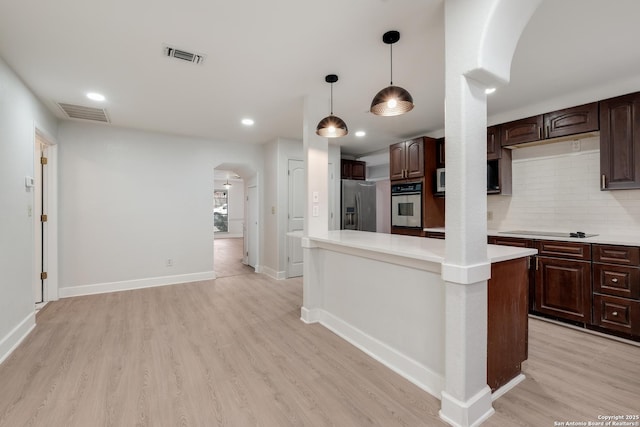 kitchen with dark brown cabinetry, light wood-type flooring, pendant lighting, stainless steel appliances, and backsplash