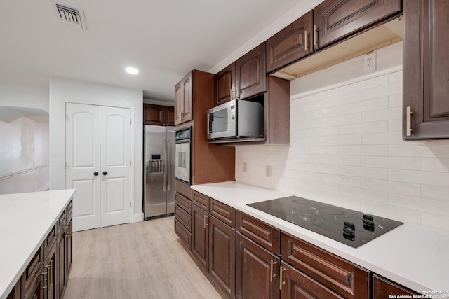 kitchen featuring tasteful backsplash, dark brown cabinets, stainless steel appliances, and light hardwood / wood-style floors