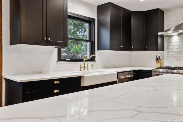 kitchen with tasteful backsplash, wall chimney exhaust hood, sink, and light stone counters