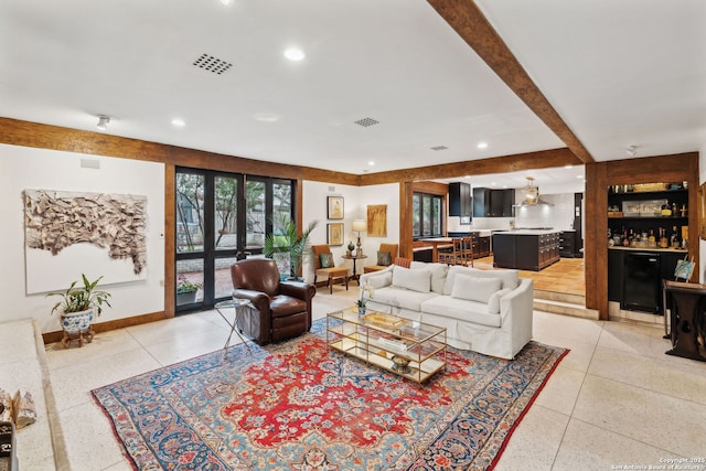 living room featuring beamed ceiling and bar area