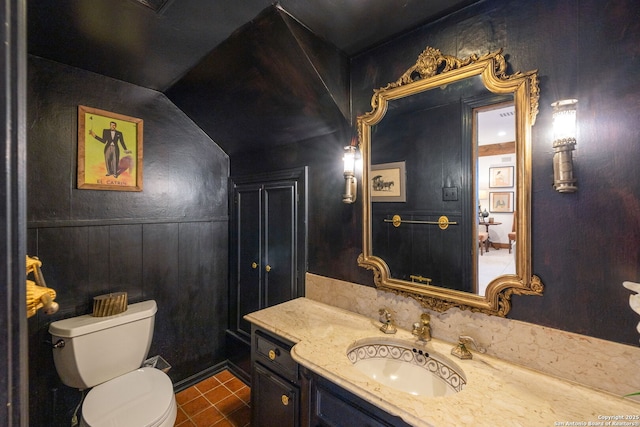 bathroom featuring lofted ceiling, vanity, toilet, and tile patterned floors