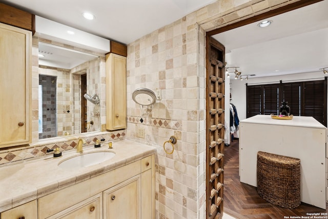 bathroom with parquet flooring, vanity, tile walls, and backsplash