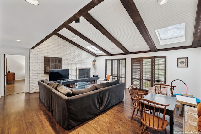 living room with a brick fireplace, dark hardwood / wood-style floors, vaulted ceiling with skylight, and brick wall