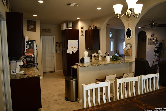 kitchen with visible vents, arched walkways, freestanding refrigerator, a peninsula, and recessed lighting