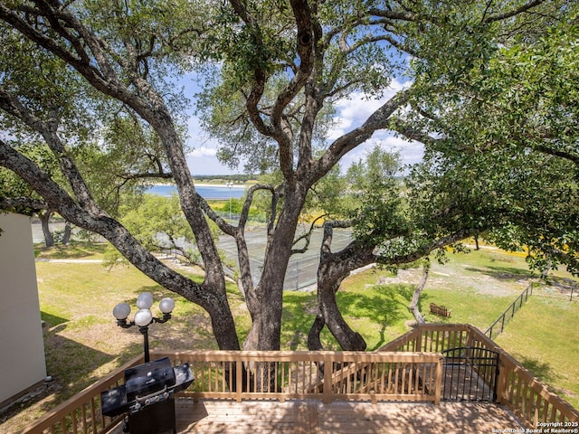 wooden terrace with a water view and a lawn