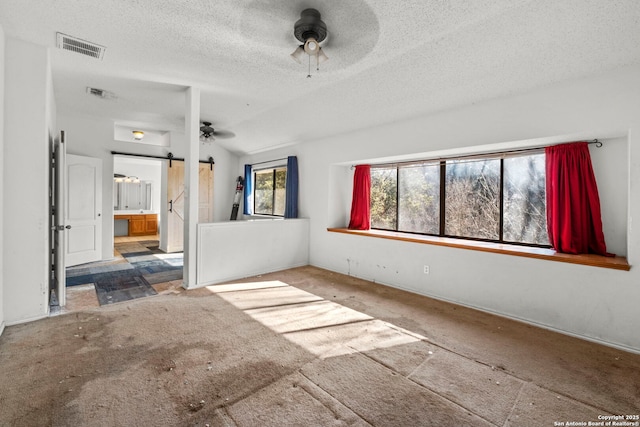 unfurnished living room with lofted ceiling, a textured ceiling, a barn door, and ceiling fan