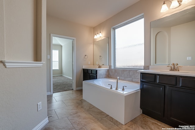 bathroom with a sink, two vanities, a bath, and baseboards