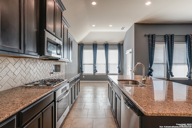 kitchen featuring light stone counters, a sink, visible vents, appliances with stainless steel finishes, and an island with sink