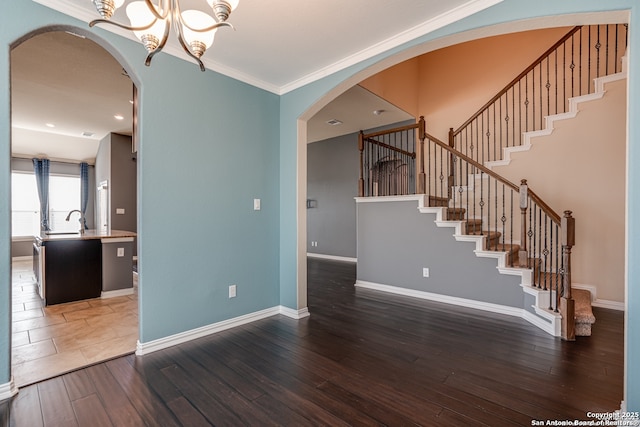 unfurnished living room featuring dark wood-style floors, arched walkways, crown molding, and baseboards