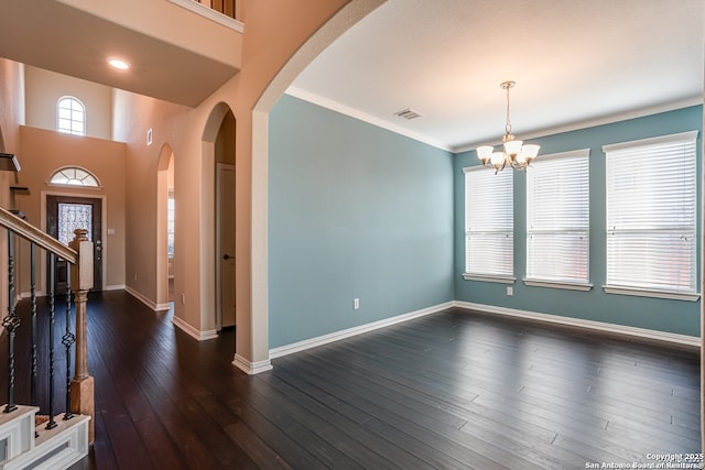 entrance foyer featuring arched walkways, a notable chandelier, baseboards, ornamental molding, and dark wood-style floors