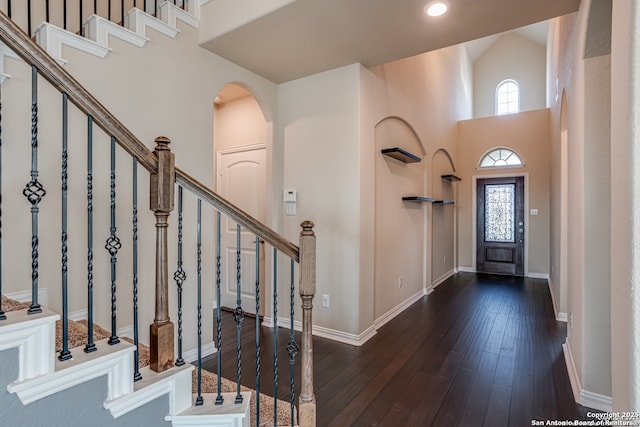 entryway with dark wood-style floors, arched walkways, recessed lighting, a high ceiling, and baseboards