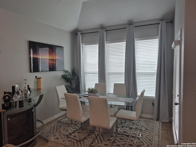 dining area with light tile patterned floors, baseboards, and vaulted ceiling