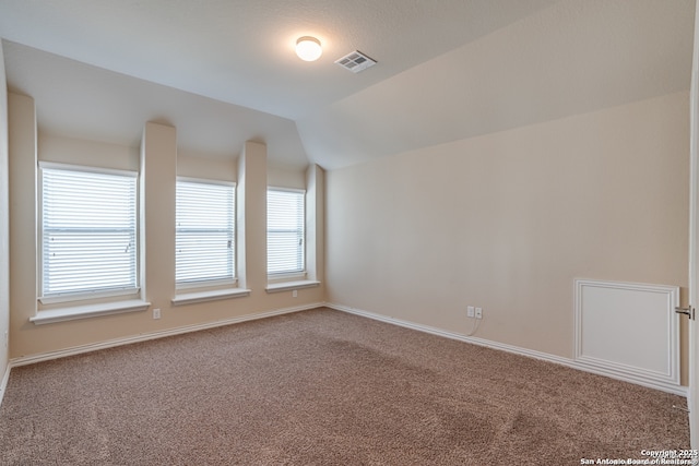 spare room with lofted ceiling, baseboards, visible vents, and carpet