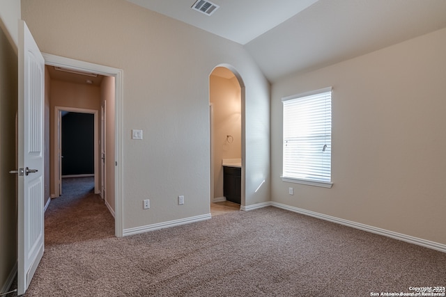 unfurnished bedroom featuring light carpet, baseboards, visible vents, arched walkways, and vaulted ceiling