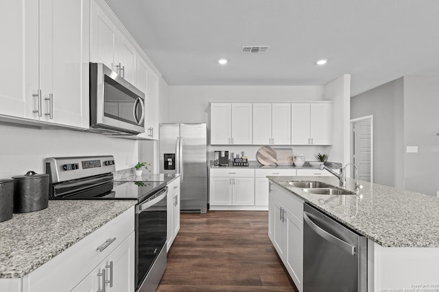 kitchen with appliances with stainless steel finishes, dark hardwood / wood-style floors, white cabinetry, sink, and a center island with sink