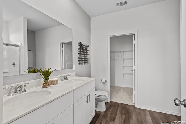 bathroom featuring a shower with door, vanity, hardwood / wood-style floors, and toilet