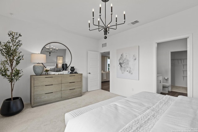 bedroom with an inviting chandelier, dark carpet, and ensuite bath
