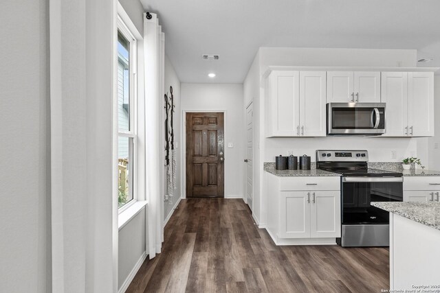 kitchen featuring white cabinetry, light stone counters, stainless steel appliances, and a healthy amount of sunlight