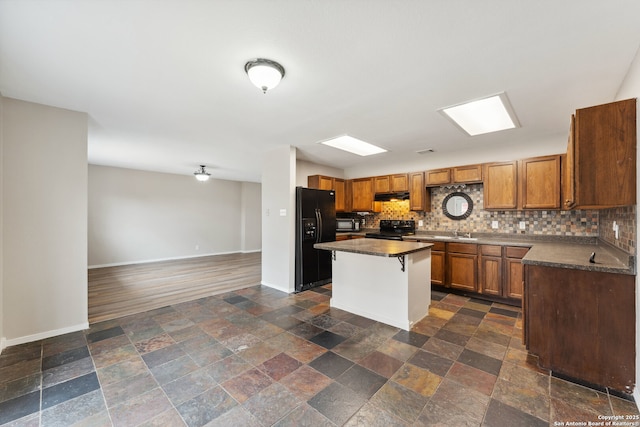 kitchen featuring tasteful backsplash, a kitchen bar, a kitchen island, and black appliances